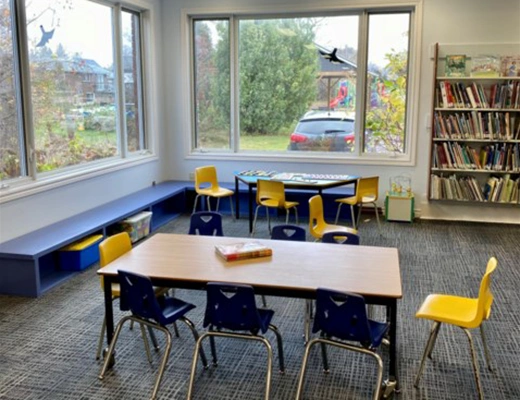 photo of tables with chairs inside Markdale library showing very large windows with natural light