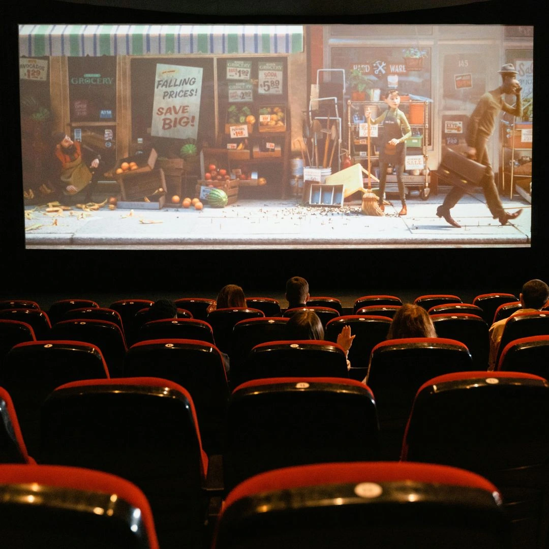A movie theater interior filled with people seated in rows, focused on the screen in front of them.
