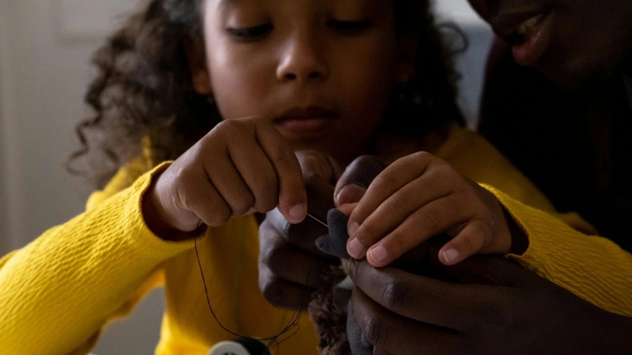 A man and a young girl collaborate on a project, focused on their work together at a table.