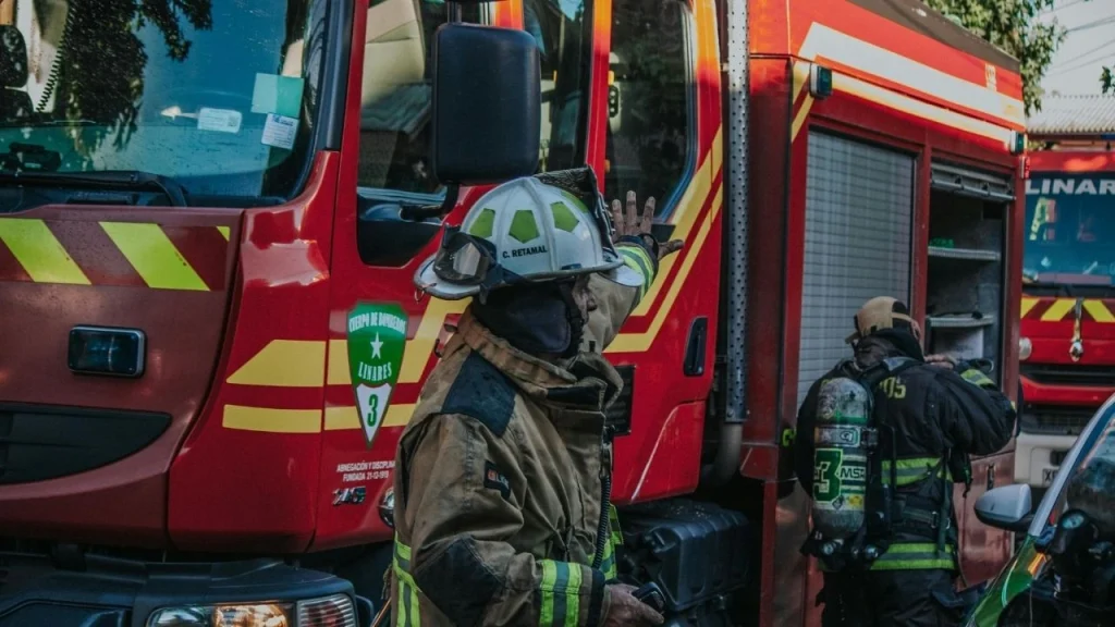 Firefighters stand in the street beside a fire truck, preparing to respond to an emergency situation.