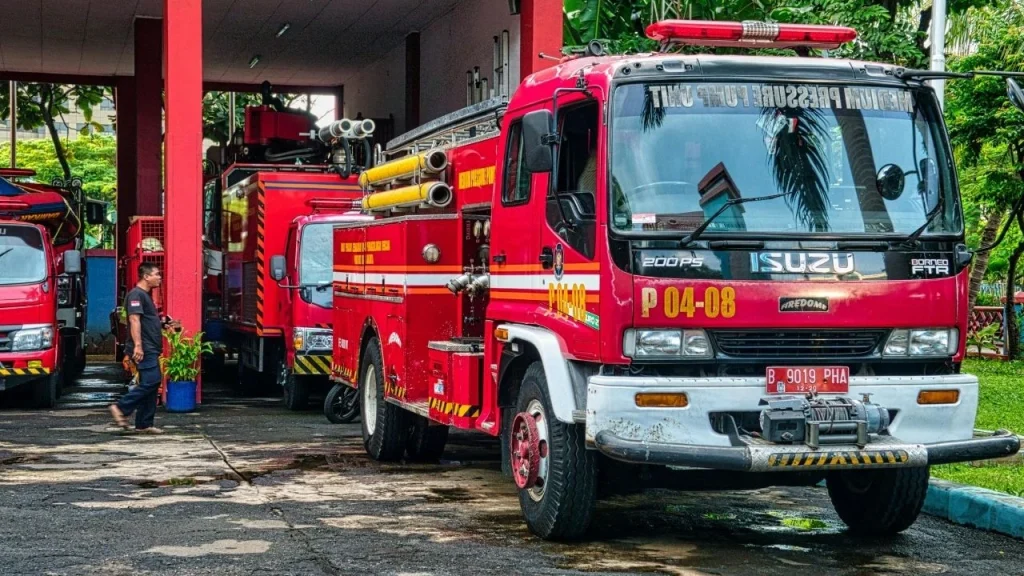 Fire trucks parked in front of a building, ready for emergency response, with clear blue skies in the background.