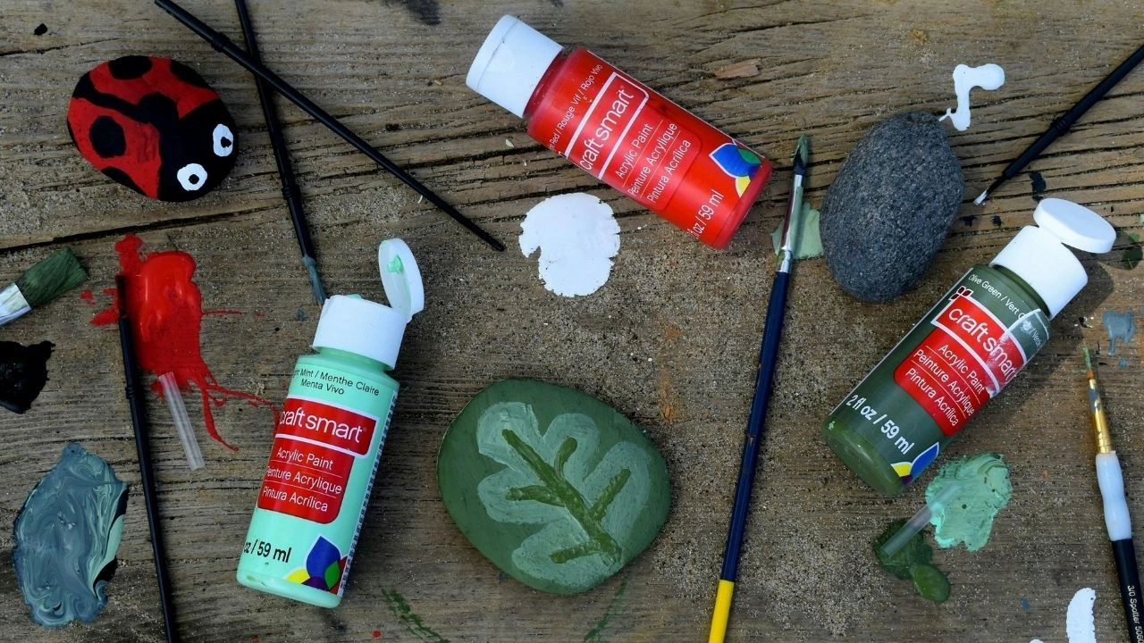 A selection of colorful paints and brushes arranged on a wooden table, showcasing an artist's workspace.