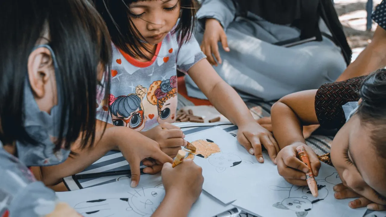 Children using their hands to draw colorful designs on paper, showcasing creativity and artistic expression.