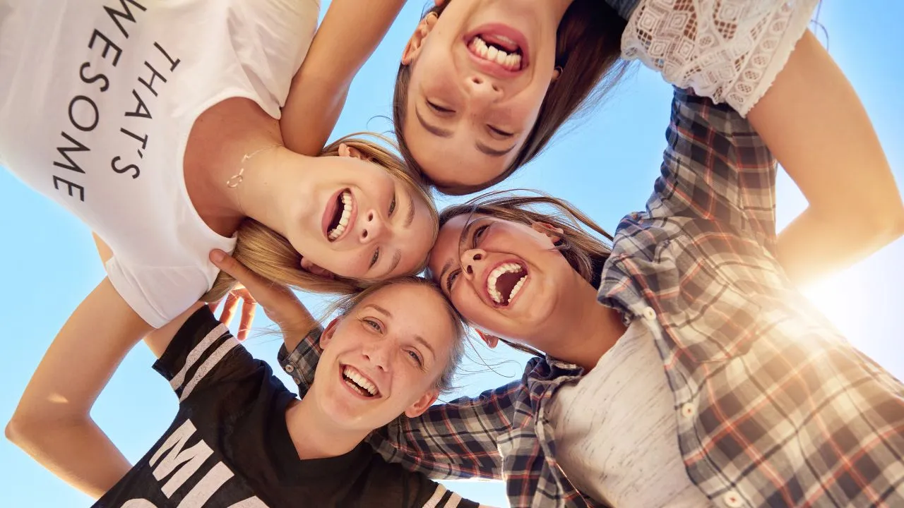 Four young women joyfully laughing together, suspended in mid-air, showcasing a moment of friendship and fun.