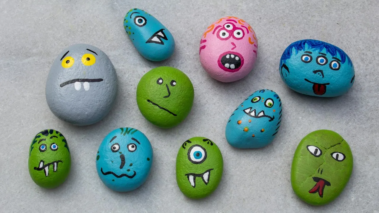 A collection of colorful painted rocks, each featuring unique facial expressions and designs.