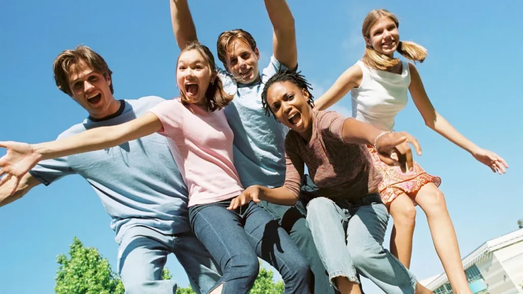 A group of young people joyfully jumping in the air against a clear blue sky.